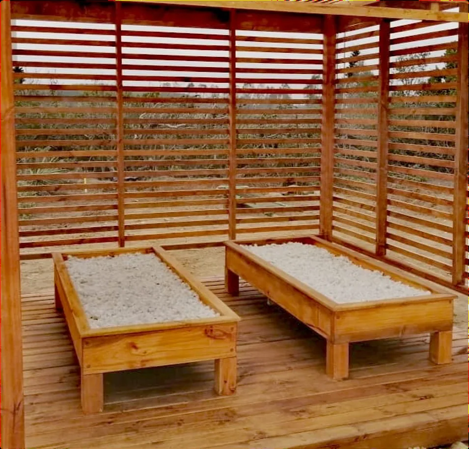 Dos camas de cuarzo terapéutico con estructura de madera bajo una pérgola con celosías y piso de deck