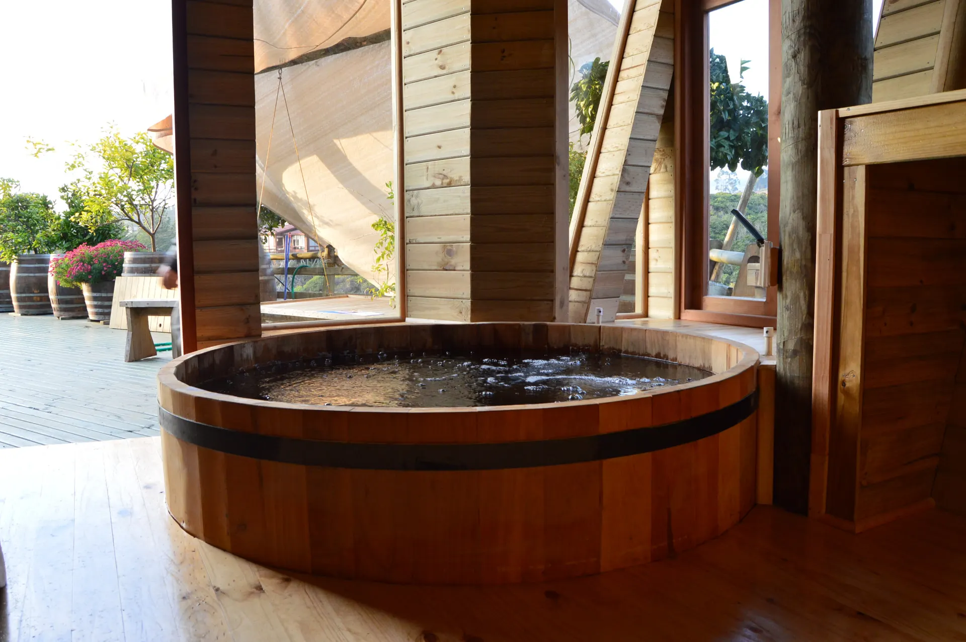 Tina caliente de ciprés con agua instalada bajo techo de madera