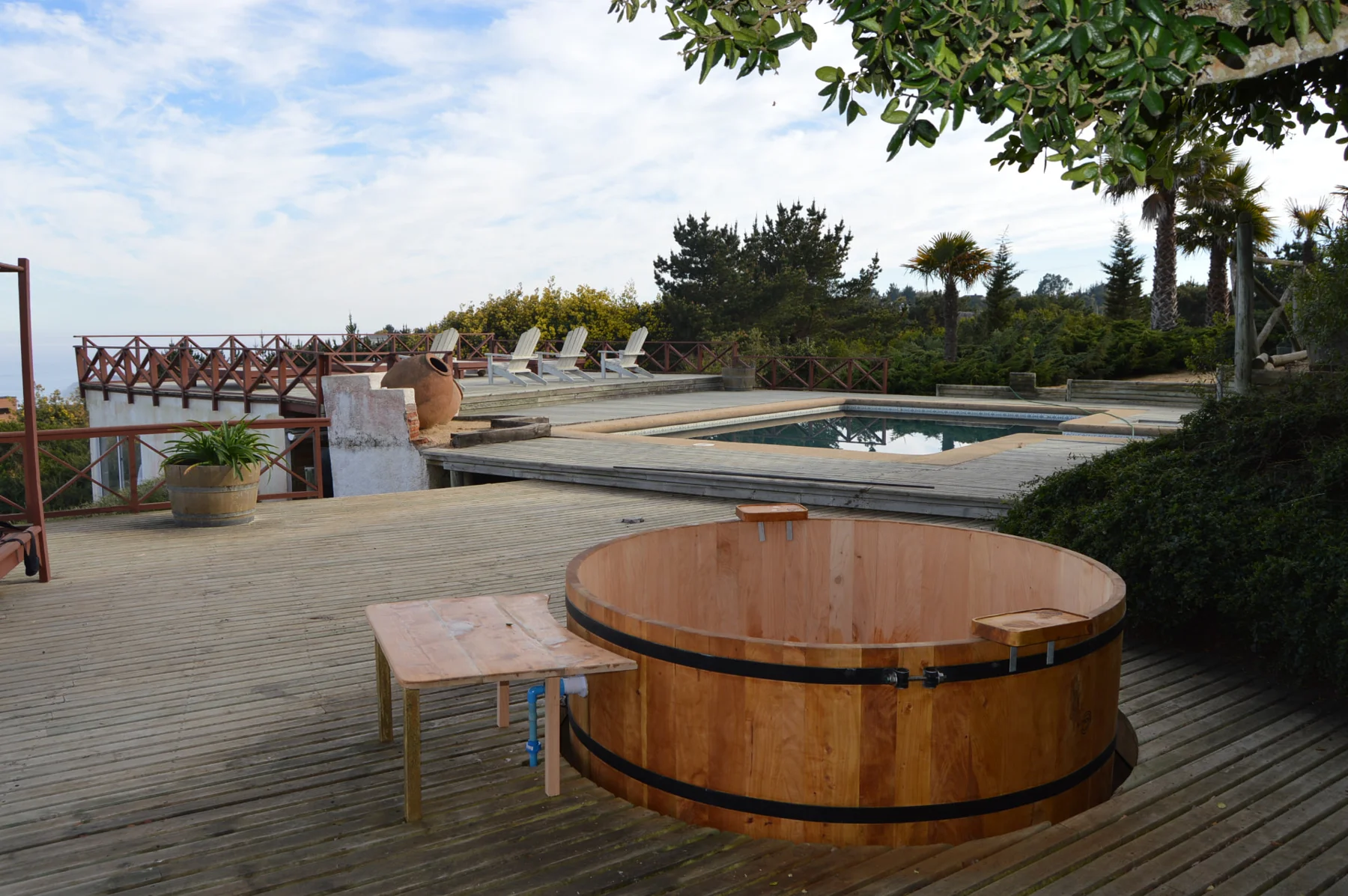 Tina de madera en terraza de una casa de playa junto a piscina